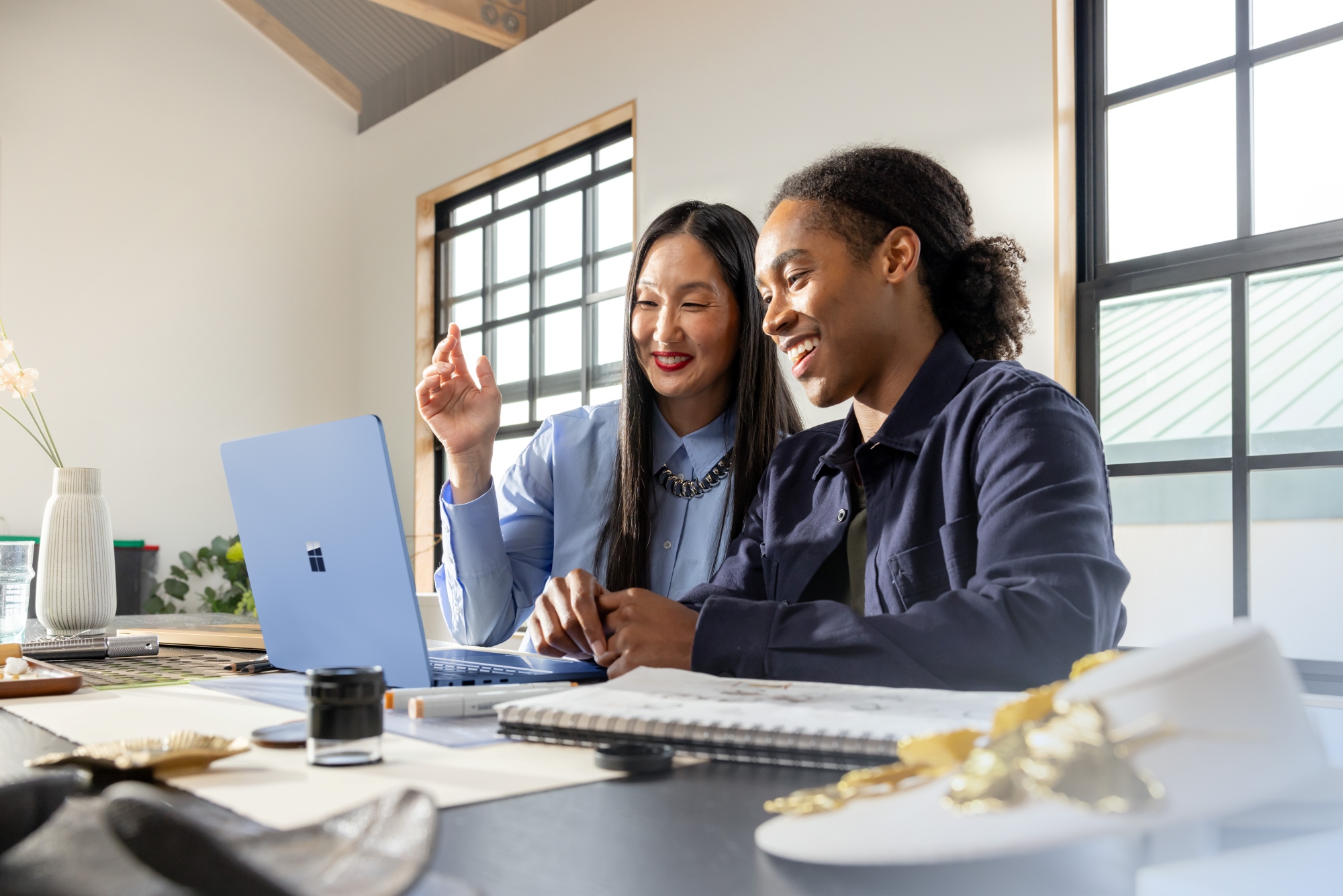 Smiling man and woman working together at Microsoft Surface laptop